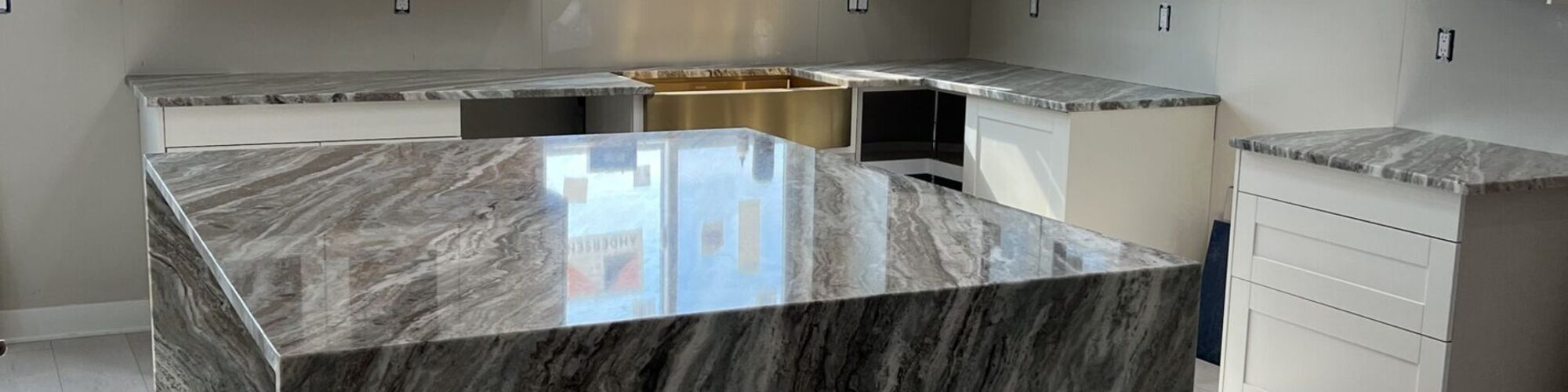 A stone island with a waterfall edge in a white kitchen